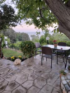 a patio with a table and chairs and a tree at Villa Gialos Rooms in Kokkino Nero +9 photos