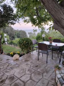 d'une terrasse avec une table, des chaises et un arbre. dans l'établissement Villa Gialos Rooms, à Kokkino Nero