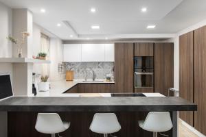 a kitchen with a large island with white chairs at Luxury Msida Circle Suites in Msida