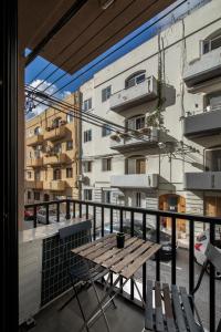 einen Balkon mit einem Holztisch und Stühlen sowie ein Gebäude in der Unterkunft Luxury Msida Circle Suites in Msida