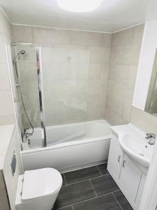 a bathroom with a toilet and a tub and a sink at Lovely Modern 2 Bed Flat /w parking, close to town in Manchester