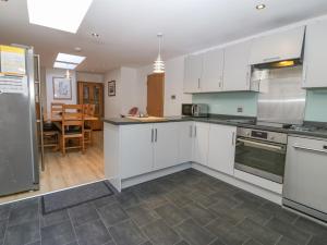 a kitchen with white cabinets and a dining room at Ty Castell in Caernarfon