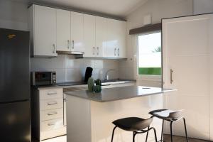 a kitchen with white cabinets and a counter and two stools at V Macaronesia in San Bartolomé de Tirajana