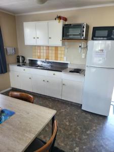 a kitchen with white cabinets and a white refrigerator at Totara Lodge Motel in Levin
