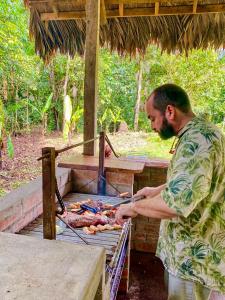 un hombre está cocinando comida en una parrilla en Wandari Lodge, en Quince Mil