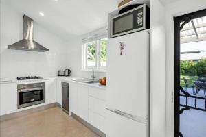 a white kitchen with a microwave and a sink at Emilias' Place - Mile End City Fringe in Keswick