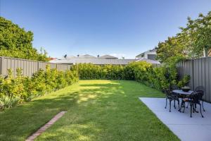 a backyard with a table and chairs and a fence at Emilias' Place - Mile End City Fringe in Keswick