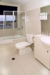 Baño blanco con aseo y lavamanos en Toowoomba Central Plaza Apartment Hotel Official, en Toowoomba