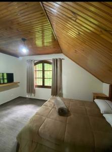 1 dormitorio con 1 cama grande y techo de madera en CANTINHO DO SOSSEGO, en Campos do Jordão