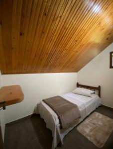 1 dormitorio con 1 cama con techo de madera en CANTINHO DO SOSSEGO, en Campos do Jordão