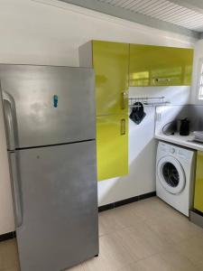 a kitchen with a refrigerator and a washing machine at Kay Sandra à 2 mn du CHU in Saint-Joseph