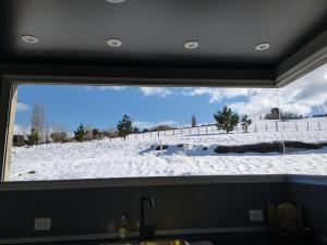 una ventana en una cocina con un campo cubierto de nieve en Las Loicas B&B en Esquel