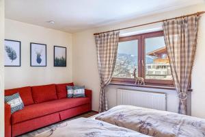 a living room with a red couch and a window at Ferienwohnung Platzhirsch Panorama View Balkon, Gartensauna, Garten, Grillplatz in Stumm