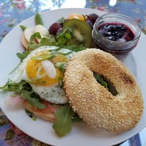 a plate with a breakfast sandwich and a bagel and fruit at Lady MacDonald Country Inn in Canmore