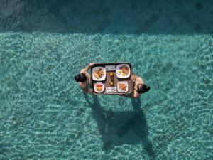 a person holding a plate of food in the water at Royal Roco Villa in Tanah Lot