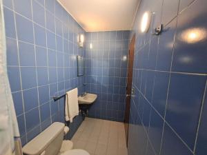 a blue tiled bathroom with a toilet and a sink at Sorokaima in Caracas