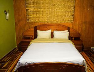 een houten bed met witte lakens en kussens bij Eco Home View - Guest House in Cuzco