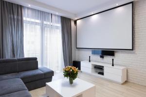 a living room with a couch and a tv at Cinema Flat Centrally Located in Warsaw