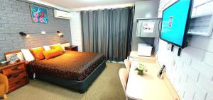 ein Schlafzimmer mit einem Bett und einem TV in der Unterkunft Goldrush Motel Young CBD in Young