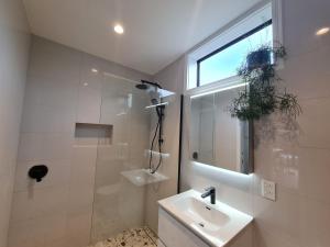 a bathroom with a sink and a shower and a window at Hidden Valley Waiheke in Palm Beach