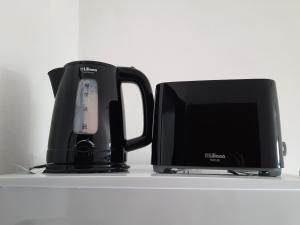 una cafetera negra y un monitor de ordenador en un estante en Departamento con COCHERA - Santa Fe en Santa Fe