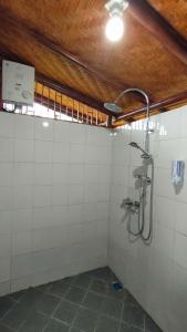 um chuveiro na casa de banho com azulejos brancos em Kelimutu Paradiso Resort em Kelimutu