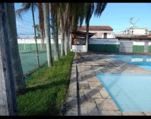 a swimming pool with palm trees next to a fence at Pousada Praia Grande - Rua Ernesto Vergara ,511 in Praia Grande