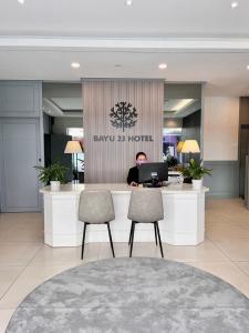 a man sitting at a desk with a laptop in a lobby at Bayu 23 Hotel in Kota Kinabalu