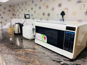 a microwave sitting on top of a kitchen counter at Lovely 2bed room AC apartment JP Nagar in Bangalore