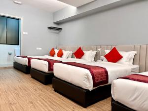 3 camas en una habitación con almohadas rojas y blancas en Bayu 23 Hotel en Kota Kinabalu