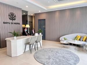 a woman is sitting at a counter in a hotel lobby at Bayu 23 Hotel in Kota Kinabalu