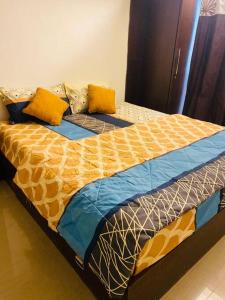 Cama con sábanas y almohadas amarillas y azules en Lovely 2bed room AC apartment JP Nagar, en Bangalore