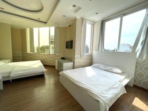 a bedroom with two beds and two windows at MILAND HOTEL in Can Tho
