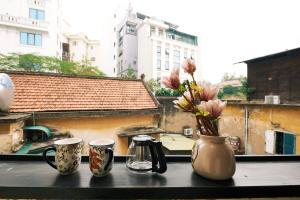 een tafel met drie kopjes en een vaas met bloemen bij Ancient villa 108m2 duplex next to Hoan Kiem Lake! in Hanoi