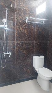 a bathroom with a toilet and a shower with brown tiles at Hotel Wisma Mangurna in Doloksanggul