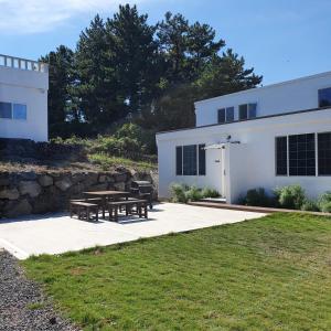 a white house with a picnic table in front of it at Jeju Damda in Jeju