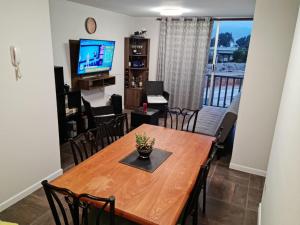 a dining room and living room with a wooden table and chairs at Acogedor, cómodo y central. in La Serena