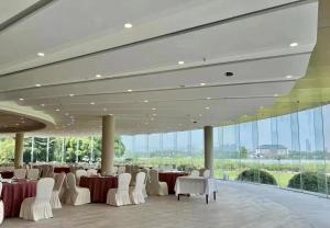無錫的住宿－无锡花园大酒店，宴会厅配有白色的桌椅和大窗户