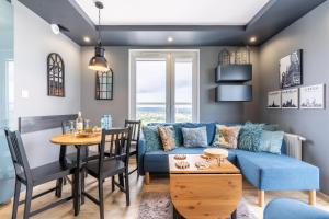 ein Wohnzimmer und ein Esszimmer mit einem blauen Sofa und einem Tisch in der Unterkunft Apartament AquaTower Oliwia & Laura REKIN in Reda