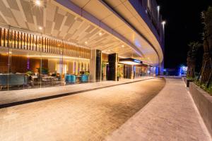 Pentacity Hotel Balikpapan في باليكبابان: مبنى امامه ممشى بالليل