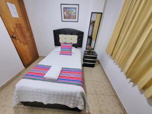 Hostal EL VIAJERO en Ollantaytambo في أولانتايتامبو: غرفة نوم صغيرة بسرير وبطانية مخططة