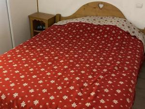 a bed with a red blanket with white flowers on it at Appartement Orcières Merlette, 2 pièces, 4 personnes - FR-1-262-180 in Orcières