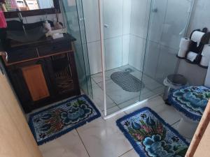 uma casa de banho com chuveiro e 2 tapetes no chão em Casa Jardim em Balneário Gaivotas