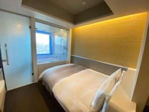a bedroom with a large bed and a window at APA Hotel Keikyukamata Ekimae in Tokyo