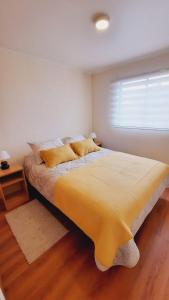 1 dormitorio con 1 cama grande con manta amarilla en Acogedora casa en Castro, en Castro