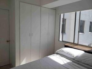 ein Schlafzimmer mit einem Bett und einem großen Fenster in der Unterkunft Apartamento pequeño y acogedor muy bien ubicado. in Quito