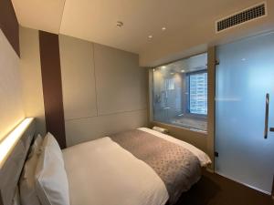 a small bedroom with a bed and a window at APA Hotel Keikyukamata Ekimae in Tokyo