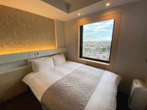 a bedroom with a white bed and a window at APA Hotel Keikyukamata Ekimae in Tokyo