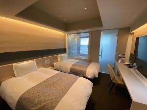 APA Hotel Keikyu Kamata-Ekimae في طوكيو: غرفة فندقية بسريرين ومكتب