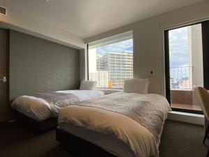 two beds in a hotel room with a large window at APA Hotel Keikyukamata Ekimae in Tokyo